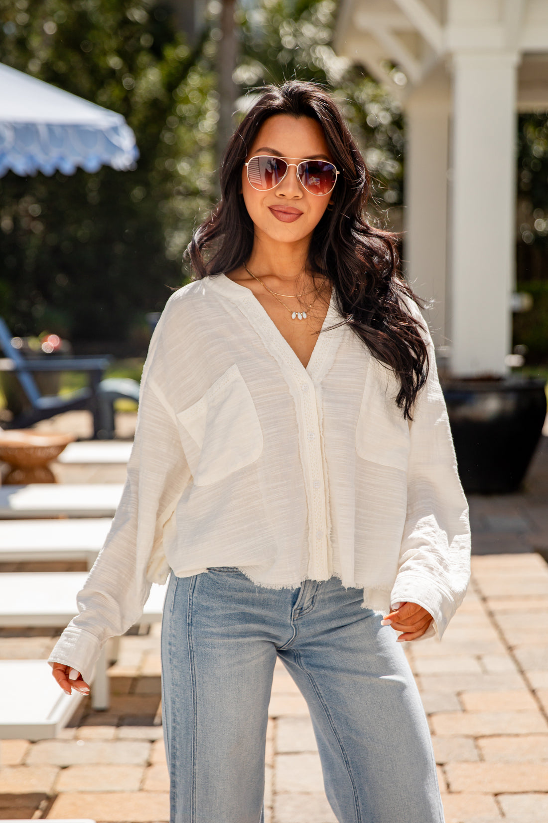 Woman wearing a white blouse and light blue jeans outdoors.
