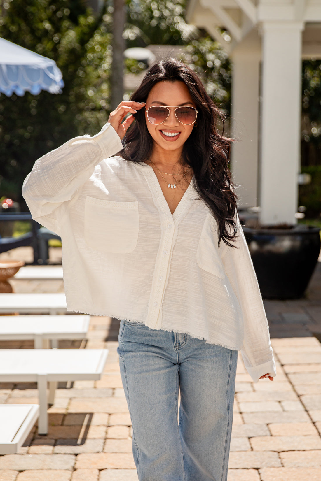 Woman wearing a light-colored blouse and sunglasses outdoors