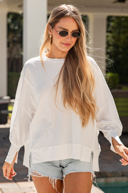 Woman wearing a white blouse and denim shorts by a poolside.