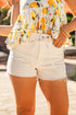 Person wearing a floral top with yellow flowers and white shorts on a blurred background