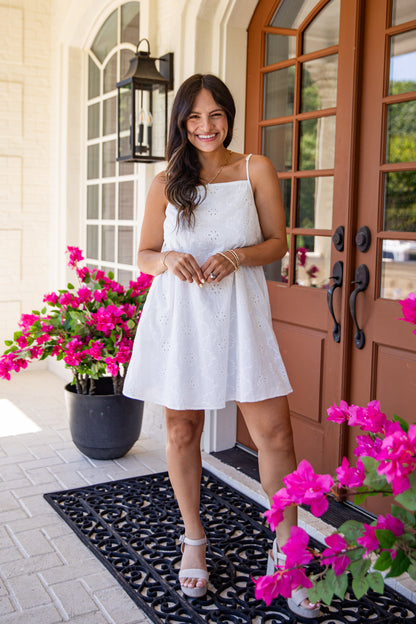 Woman in a white dress standing in front of a door with pink flowers.