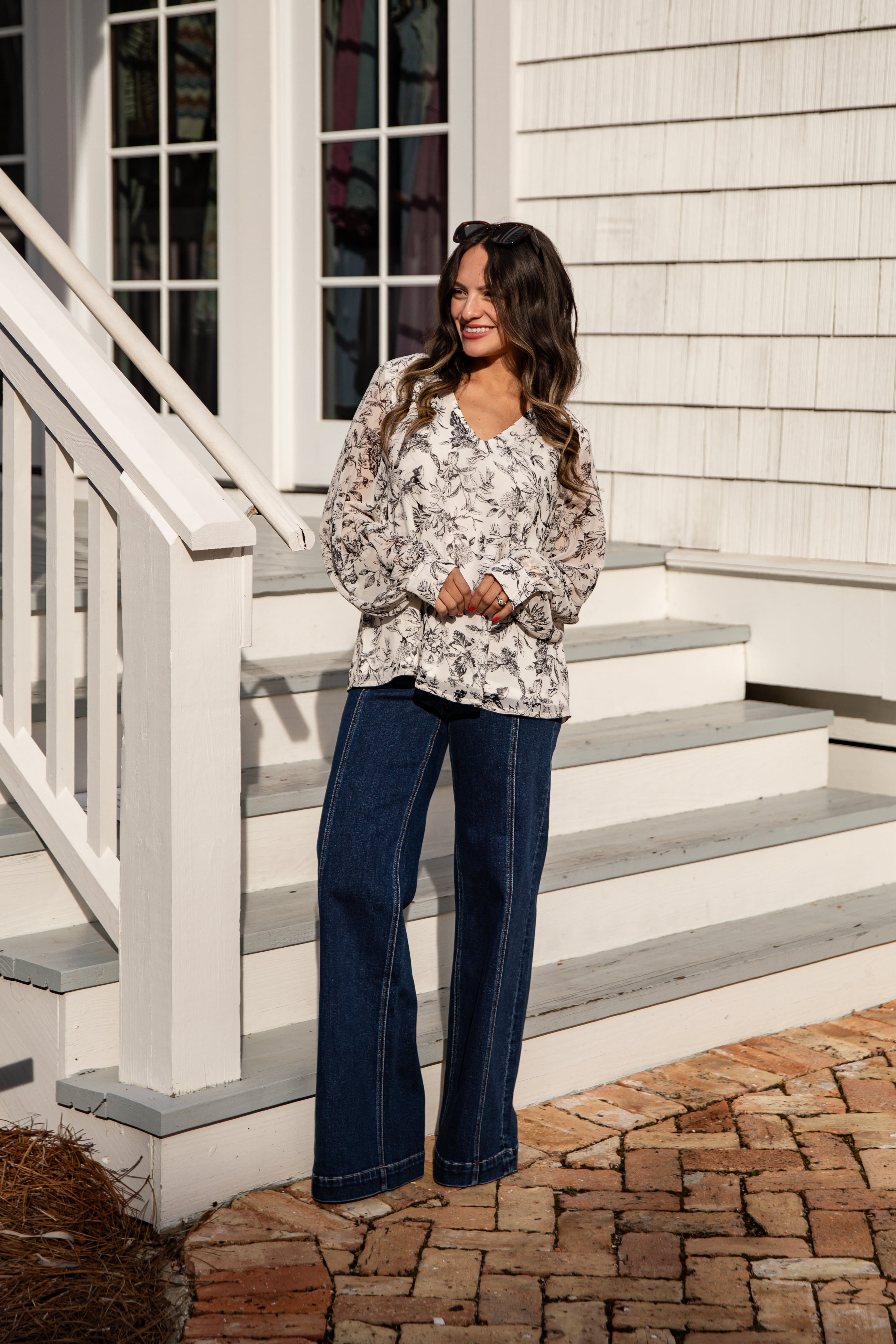 Woman standing on a staircase in front of a white house