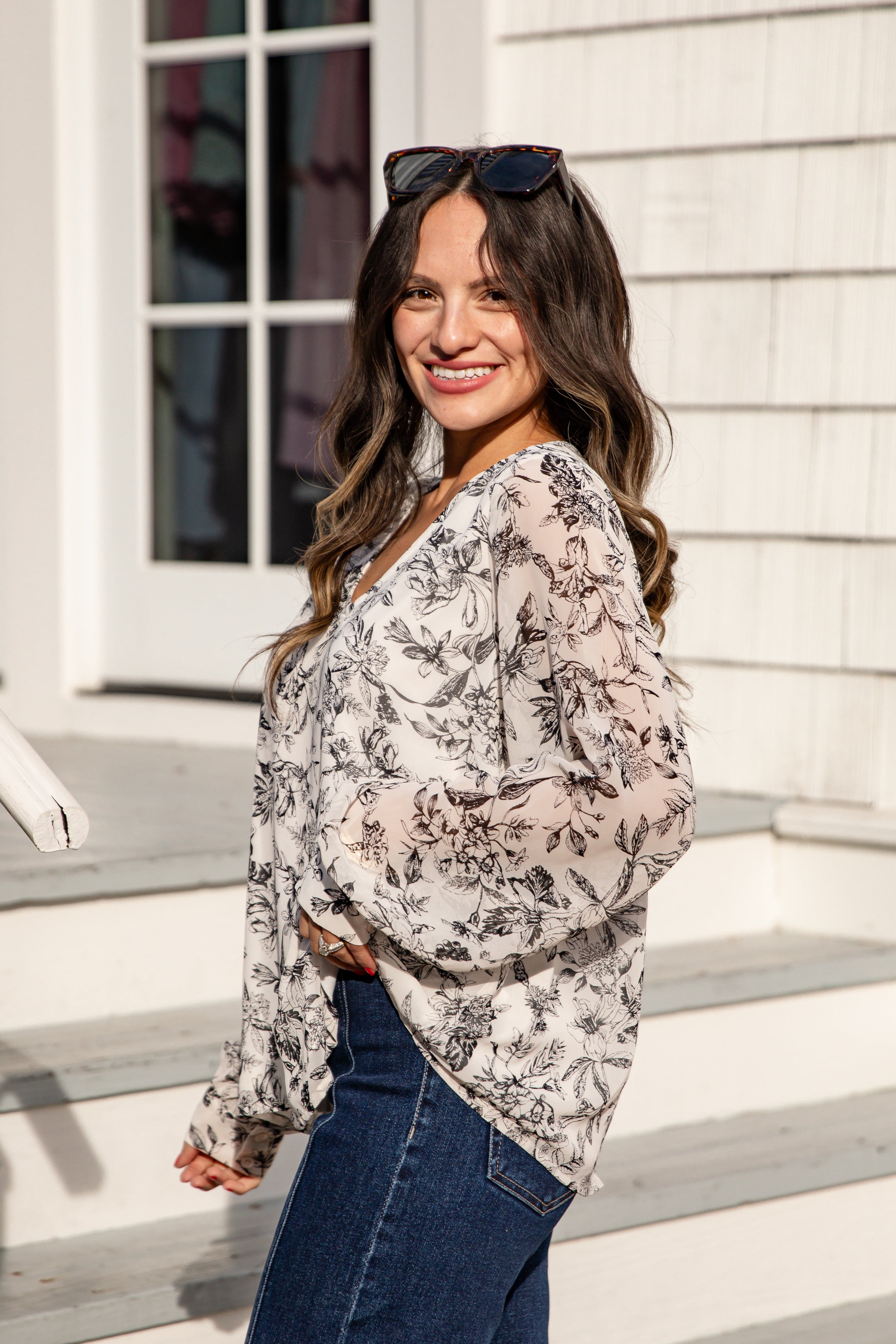 Woman wearing a floral blouse and sunglasses on a staircase