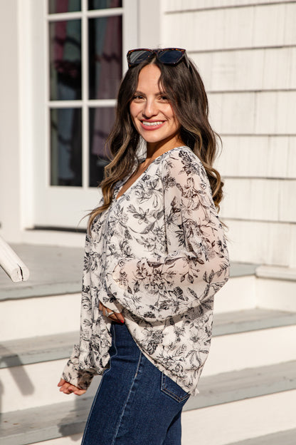 Woman wearing a floral blouse and sunglasses on a staircase