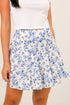 Woman wearing a white floral skirt with blue flowers on a plain background