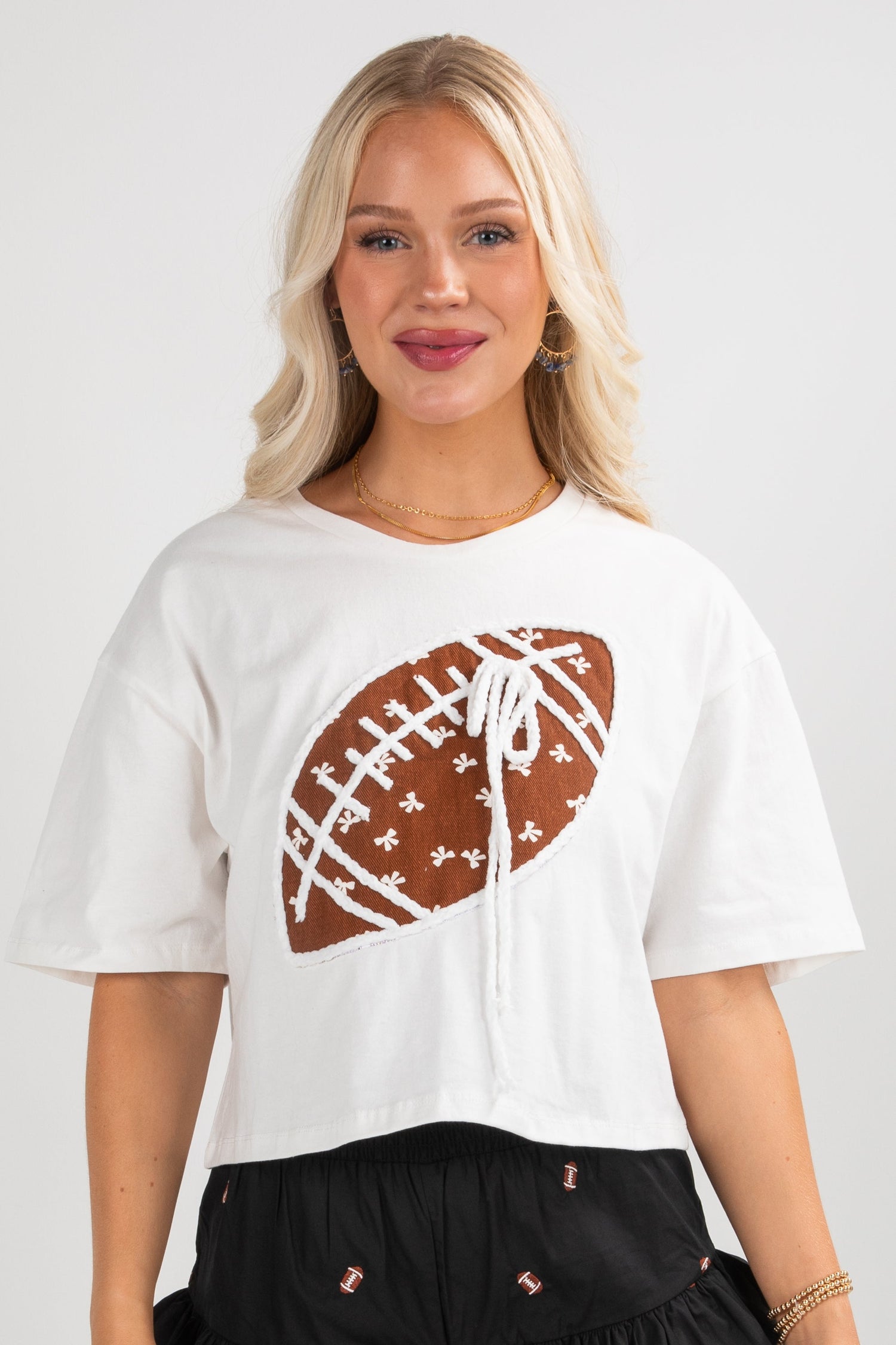 Woman wearing a white t-shirt with a football graphic on a plain background