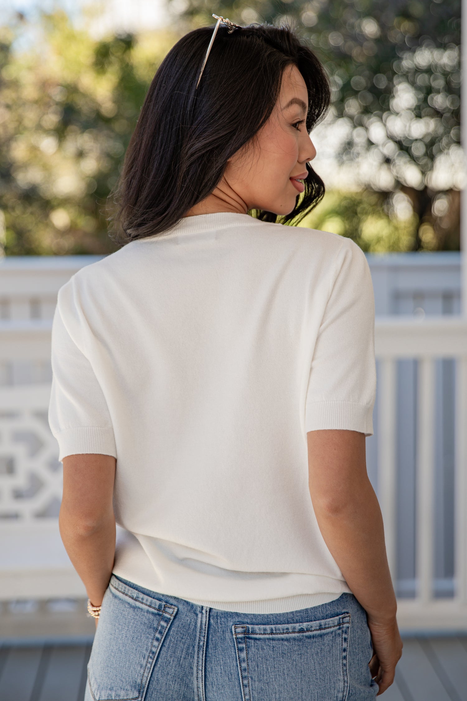 Woman wearing a white shirt and blue jeans on a blurred outdoor background