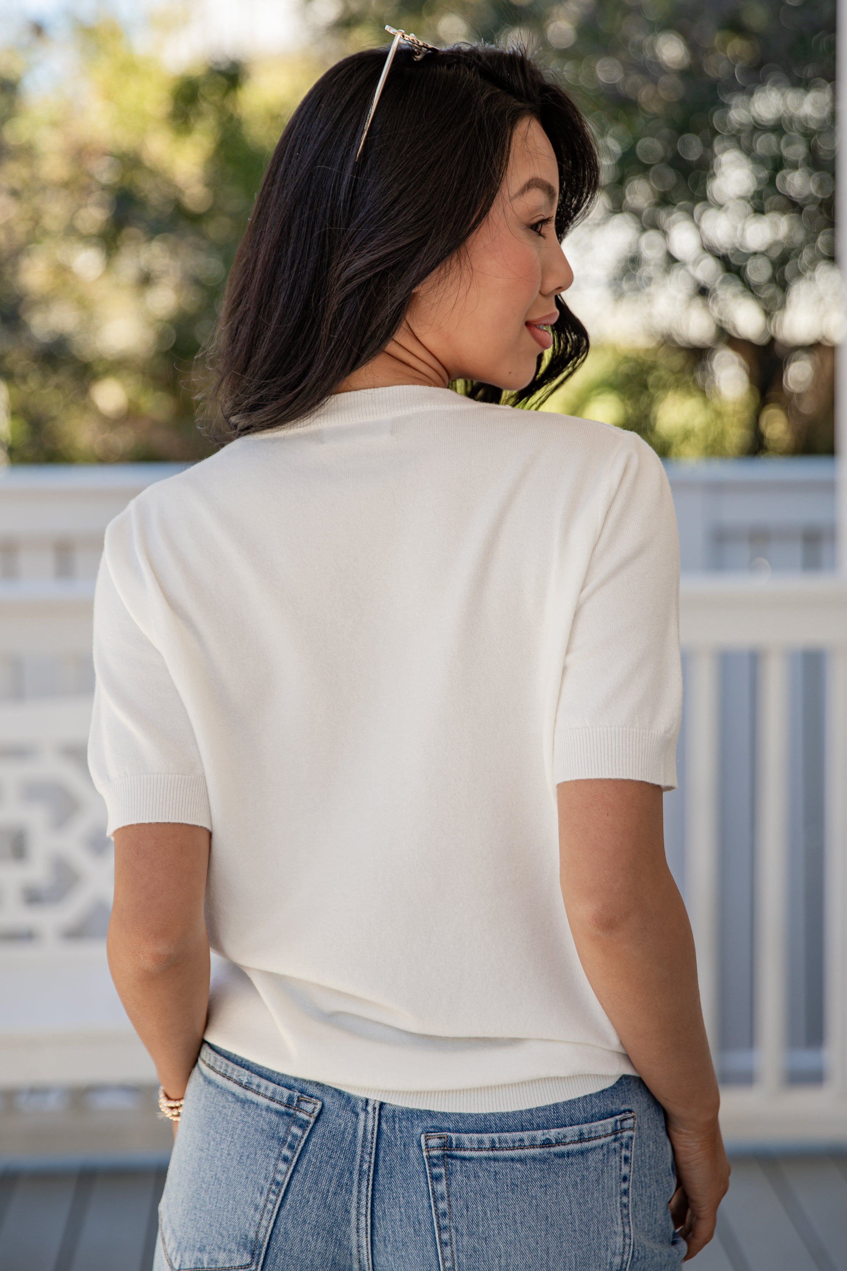 Woman wearing a white shirt and blue jeans on a blurred outdoor background