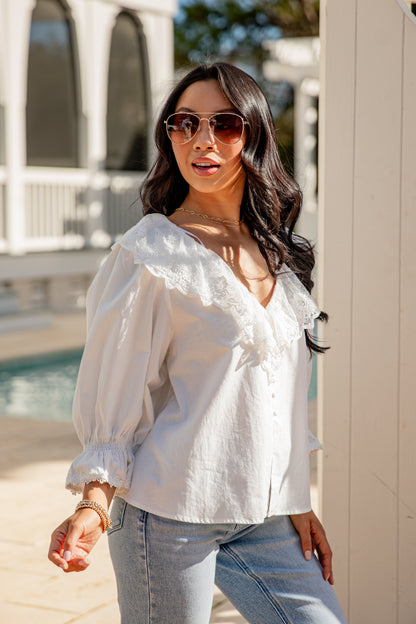 Woman wearing a white blouse and sunglasses outdoors