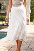 Person wearing a white lace skirt on a patio with a pool in the background