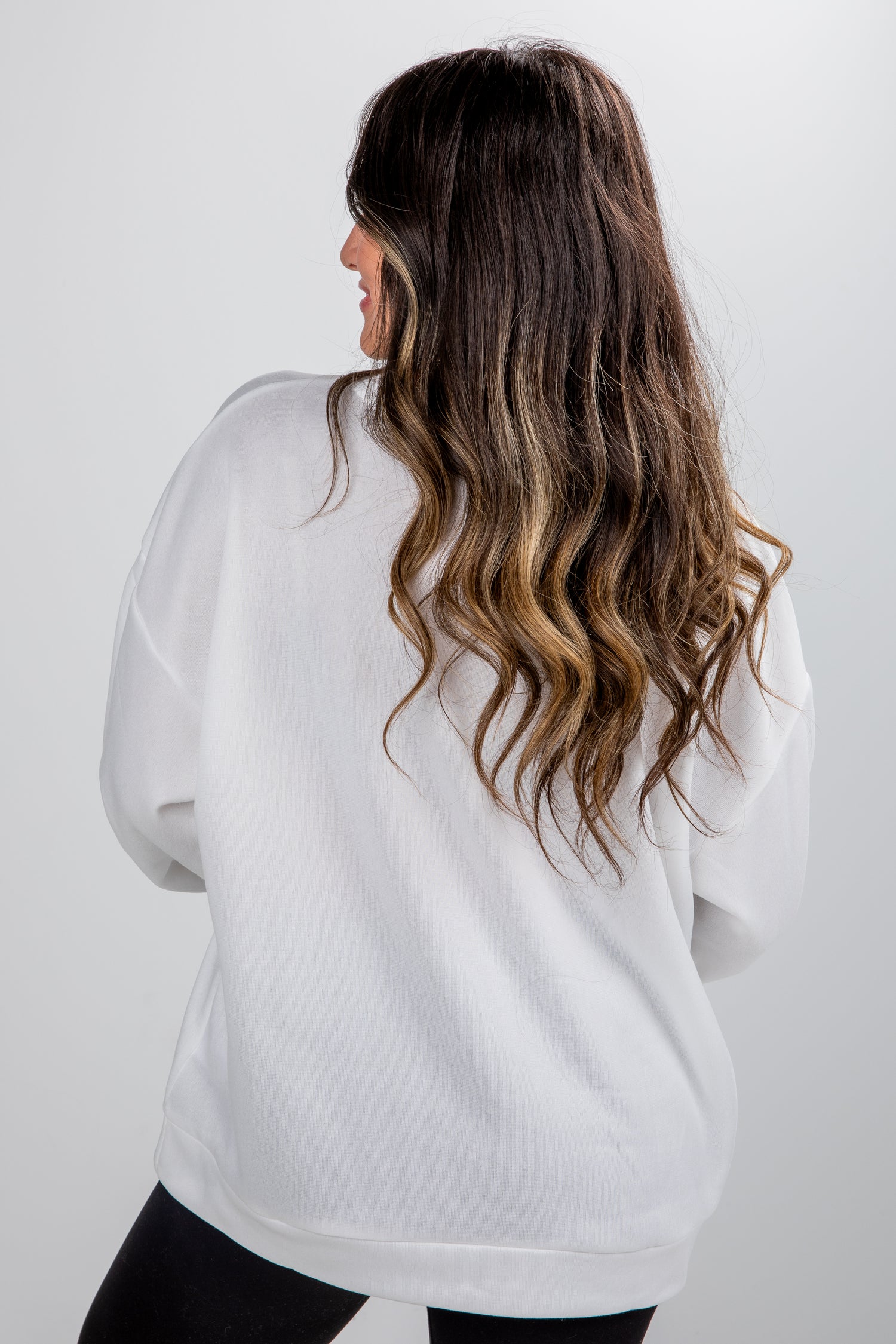 Person wearing a white oversized sweater against a plain background