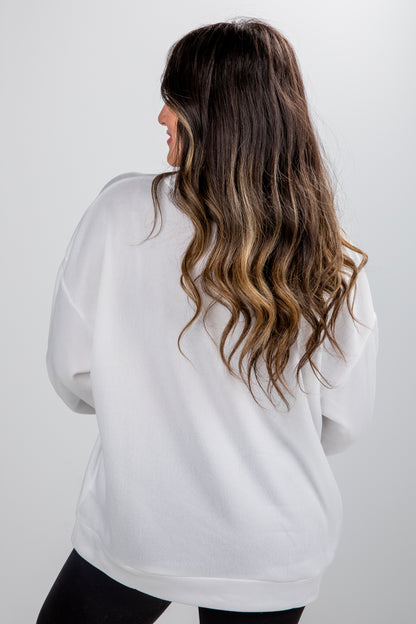 Person wearing a white oversized sweater against a plain background