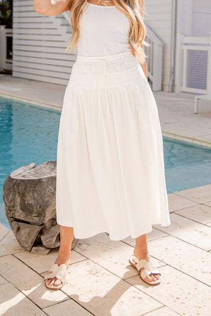 Woman in a white dress standing by a pool