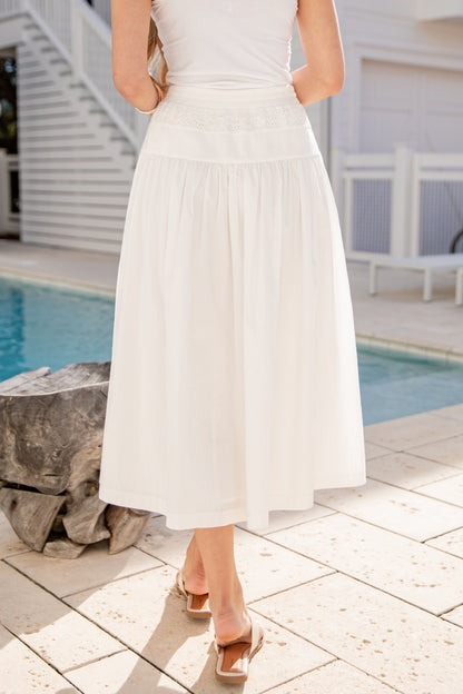 Person wearing a white dress by a poolside