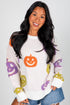 Woman wearing a white sweater with Halloween-themed pumpkins on a plain background