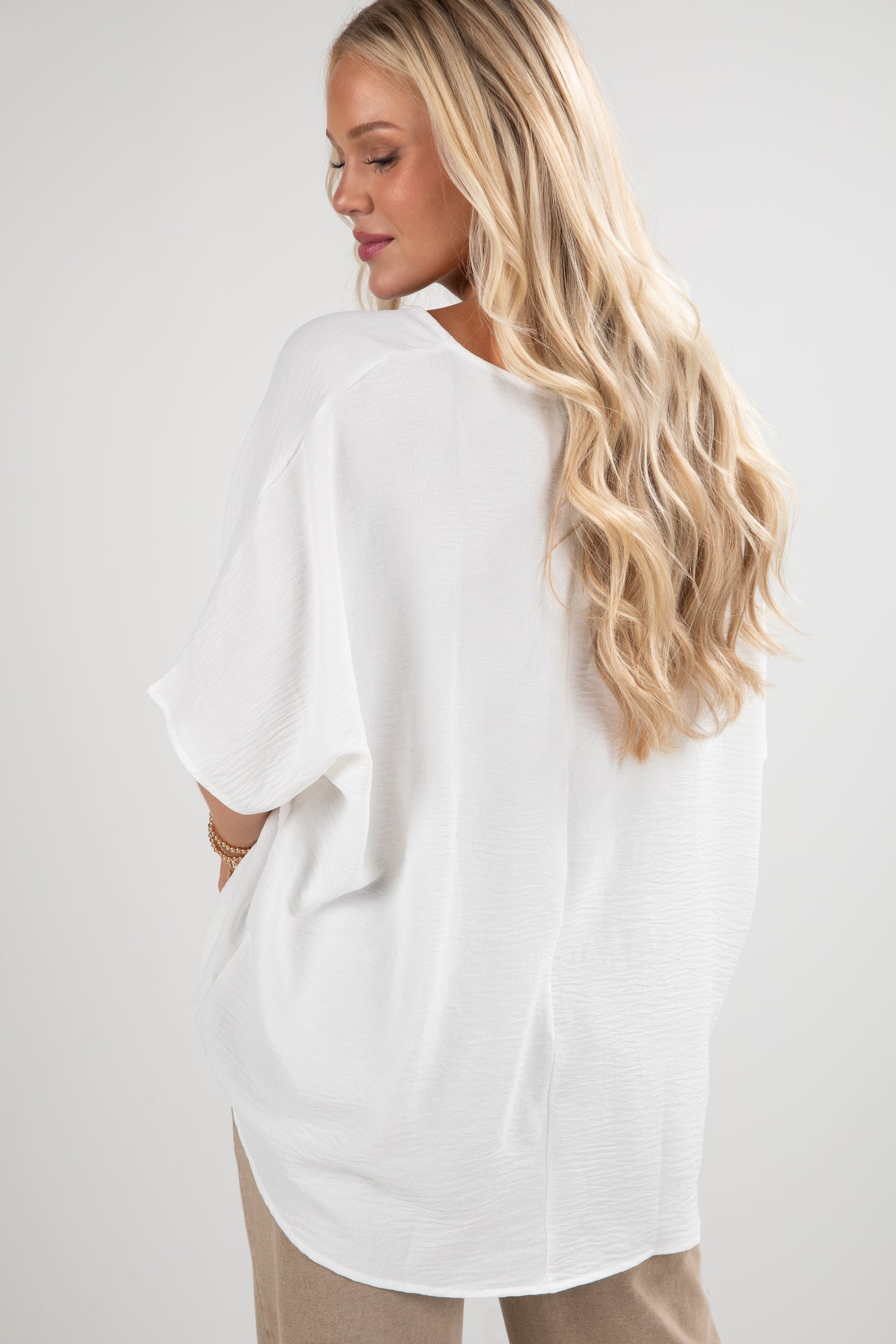Woman wearing a white oversized shirt with a plain background