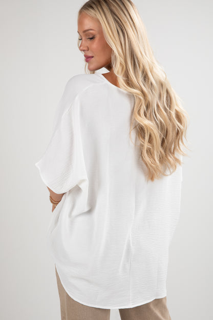 Woman wearing a white oversized shirt with a plain background