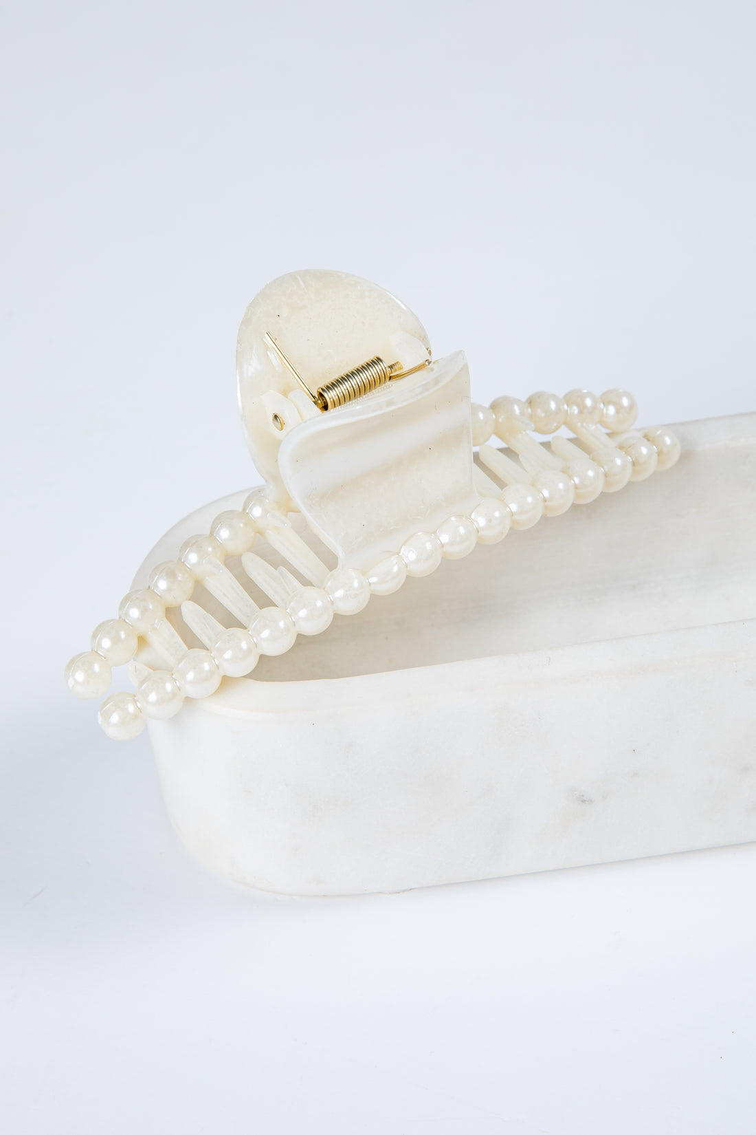 Pearl hair clip on a white surface with a light gray background