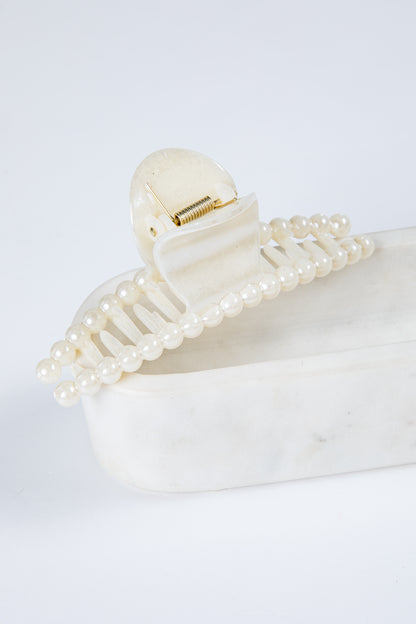 Pearl hair clip on a white surface with a light gray background