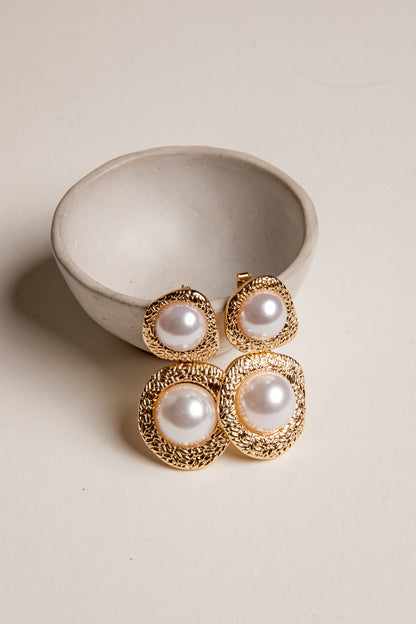 Pearl earrings with gold accents in a ceramic bowl on a beige background