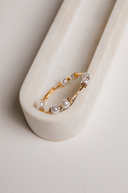 Gold hoop earring with pearls on a white background