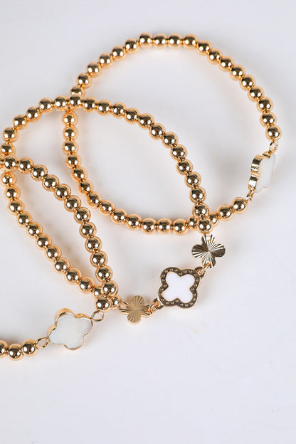 Gold beaded bracelets with star-shaped charms on a white background
