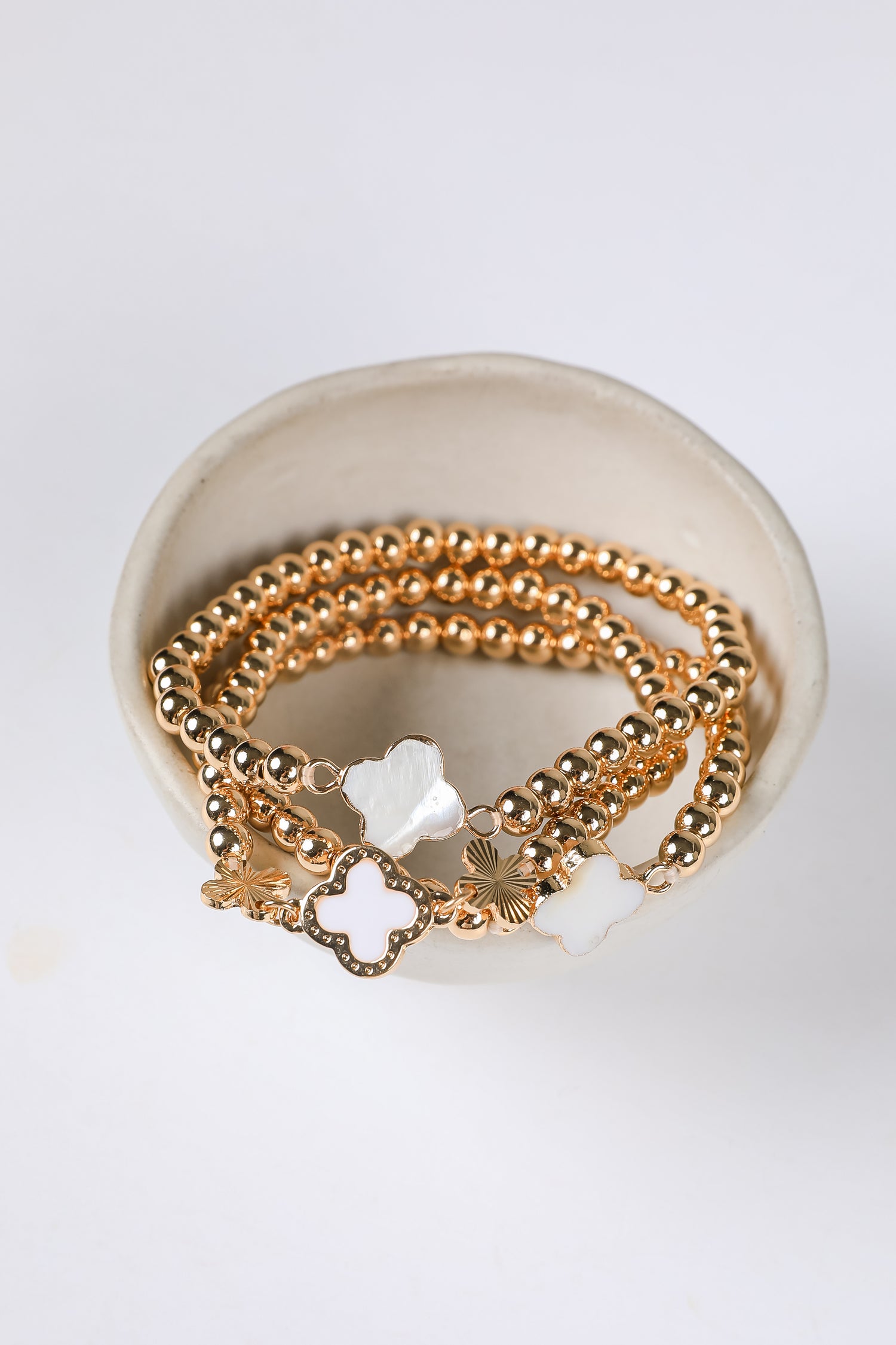 Gold bracelets with star-shaped charms on a white dish
