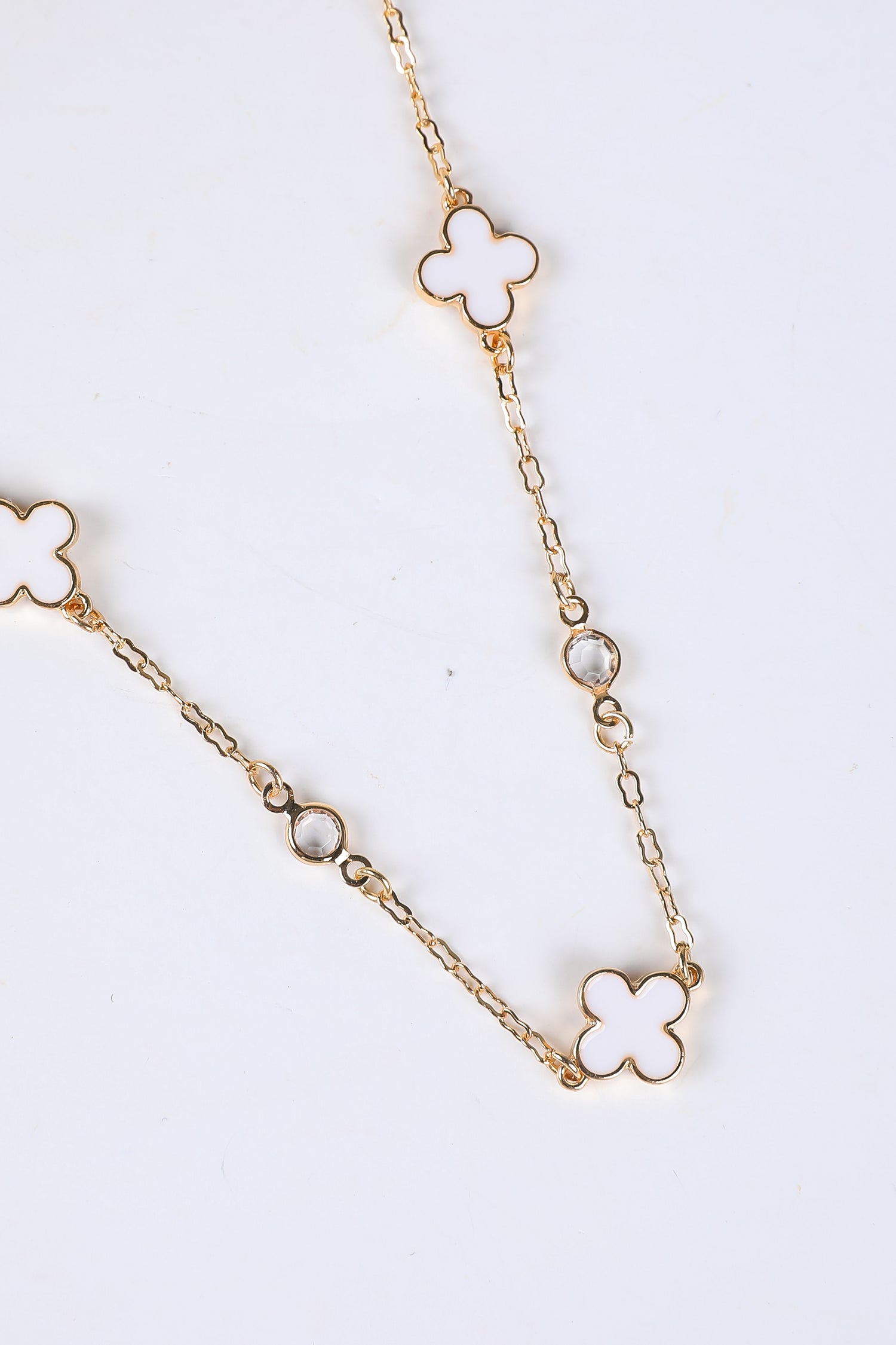 Gold chain necklace with clover-shaped pendants on a white background