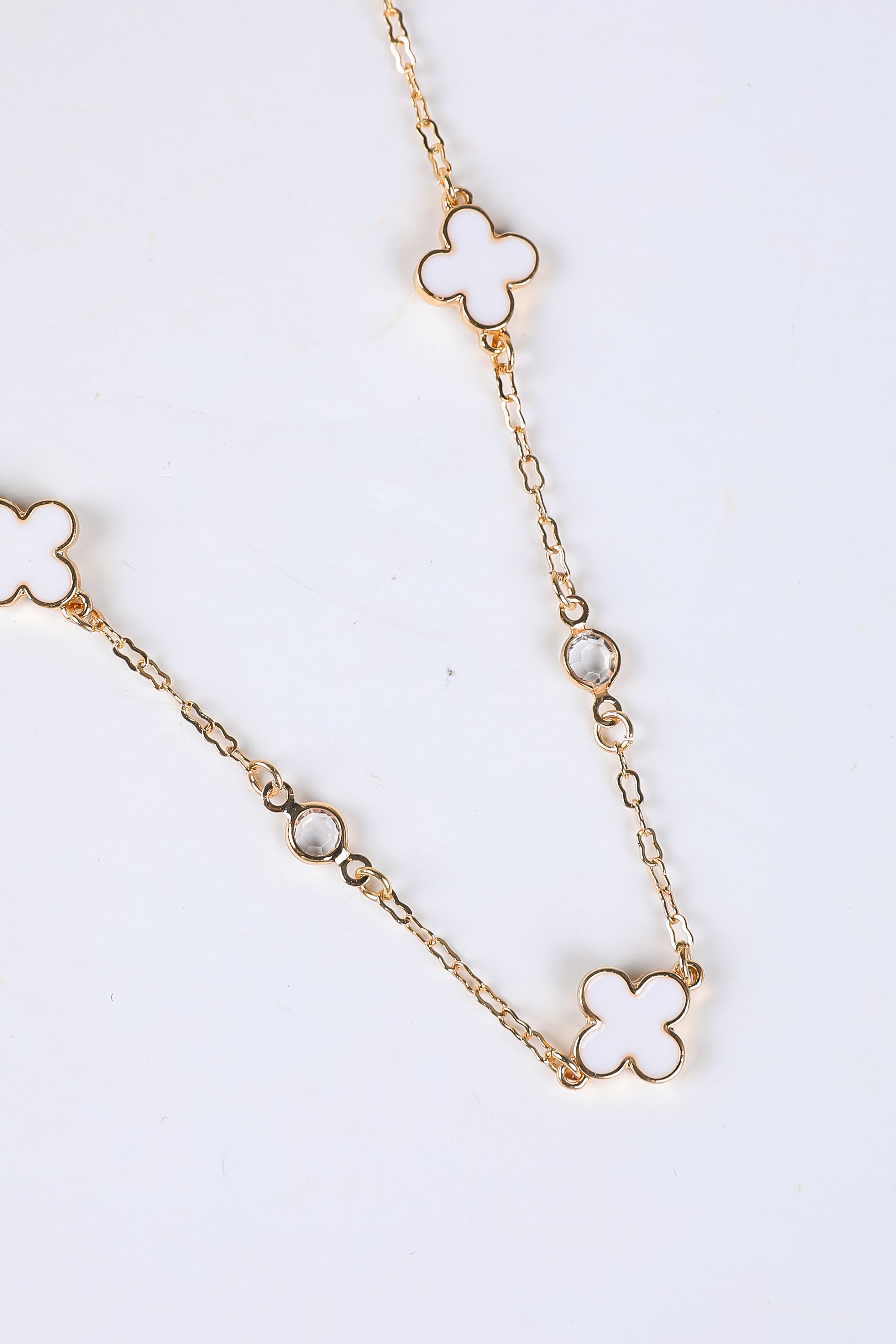 Gold chain necklace with clover-shaped pendants on a white background