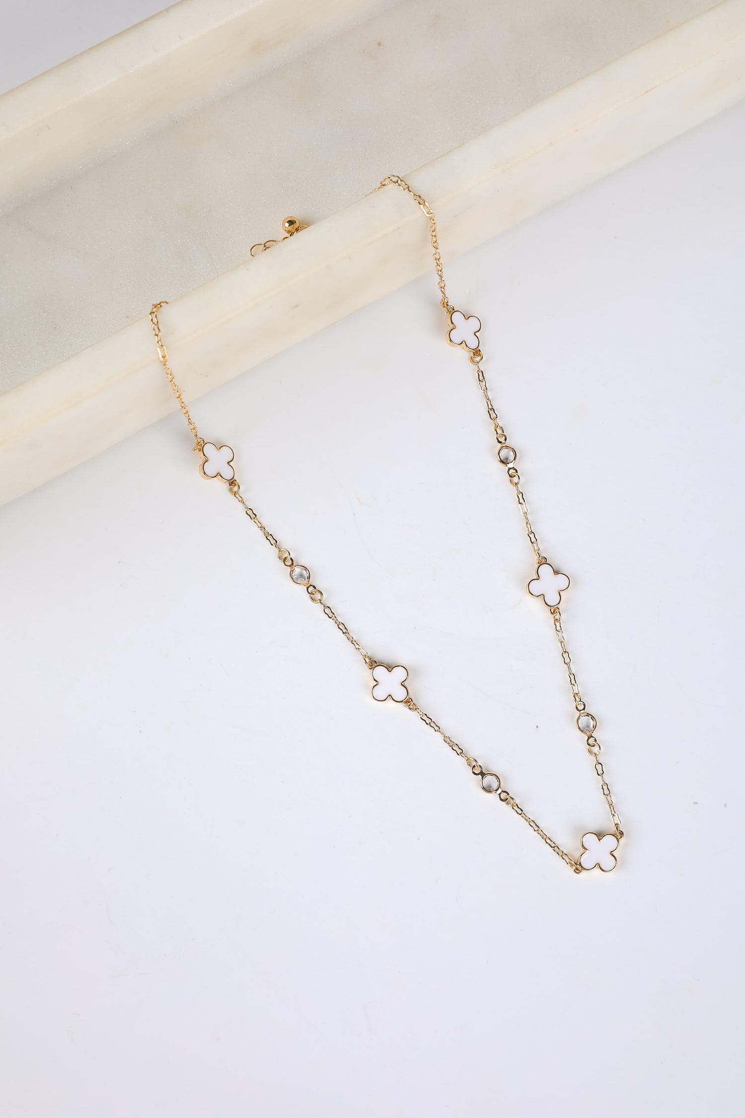 Gold necklace with floral pendants on a white surface