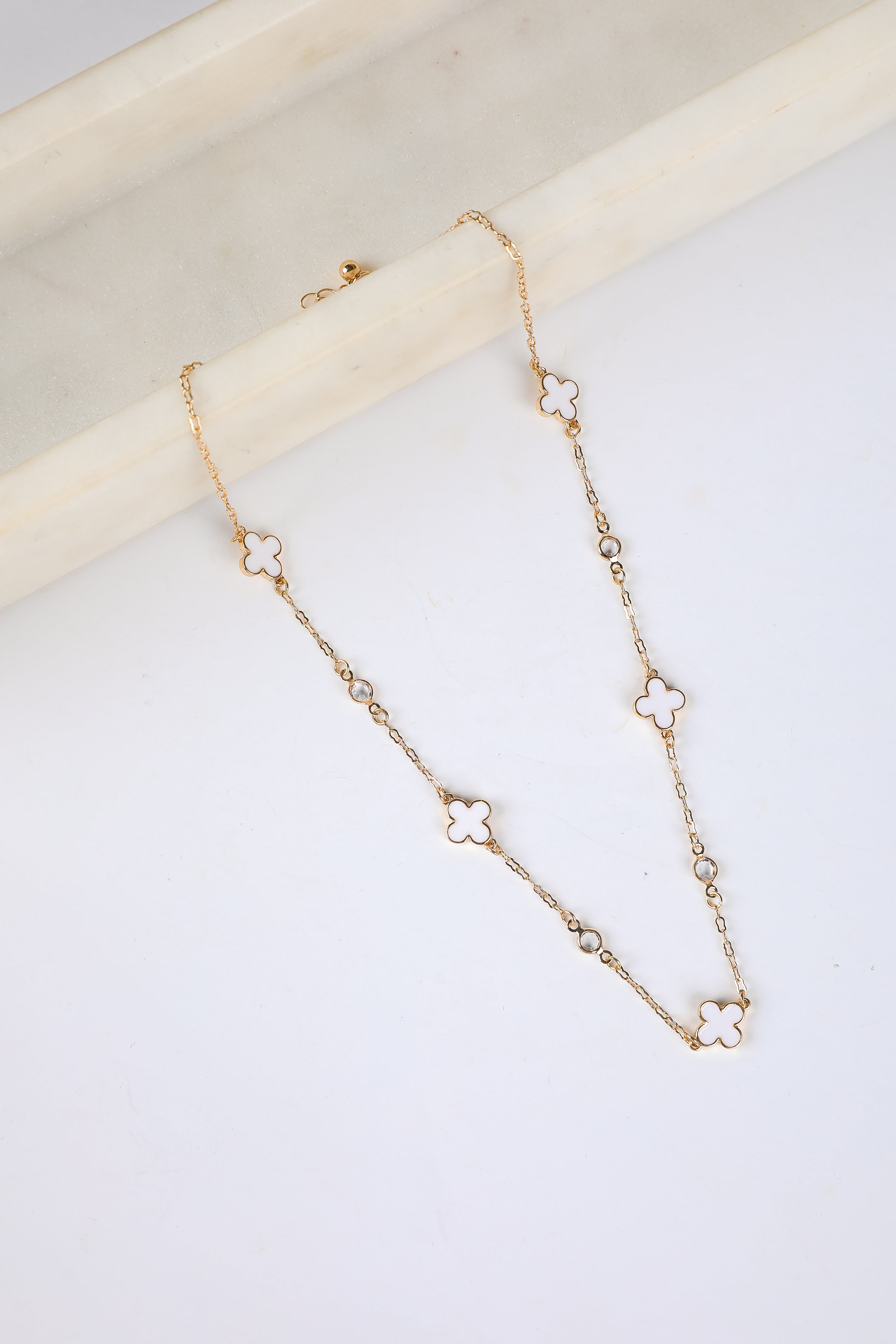 Gold necklace with floral pendants on a white surface