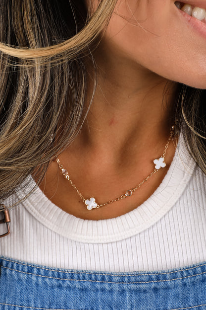 Close-up of a person wearing a delicate necklace with floral pendants.