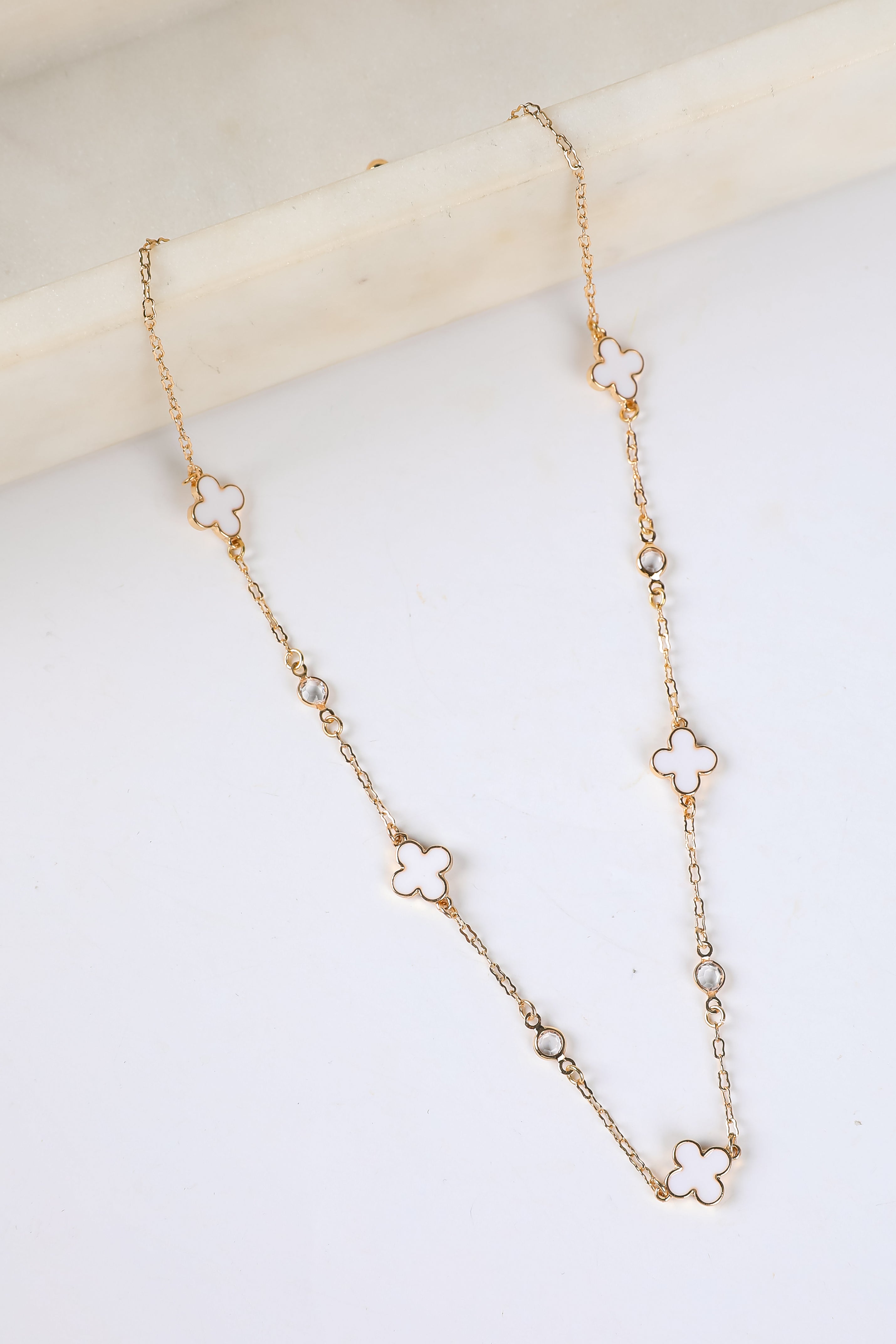 Gold necklace with clover-shaped links on a light background
