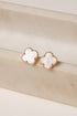 Pair of gold earrings with white stones on a beige surface