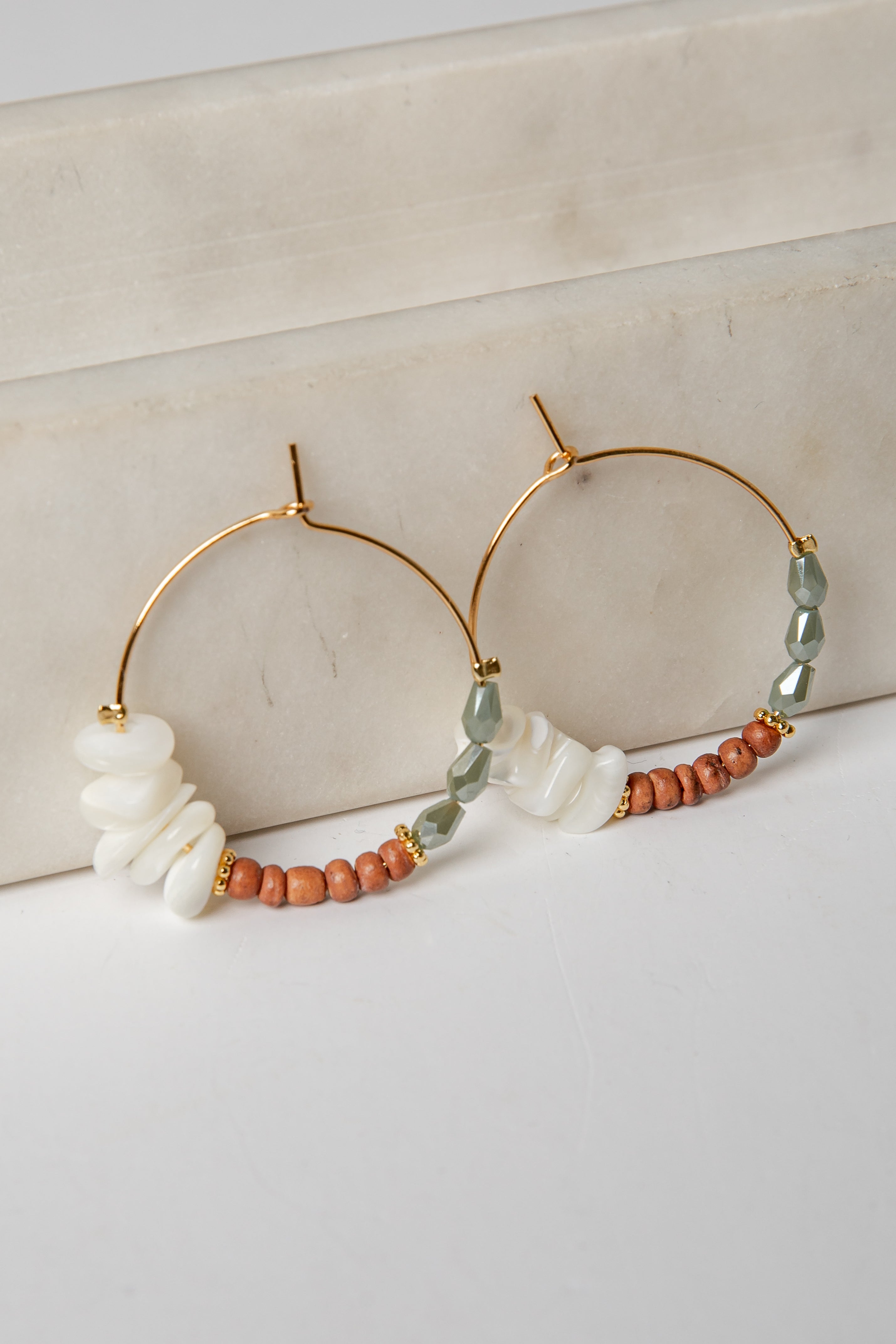 Gold hoop earrings with beads on a light background