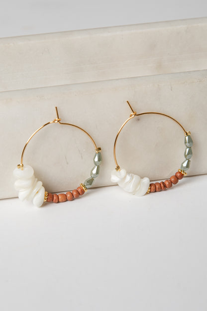 Gold hoop earrings with pearls and beads on a light background
