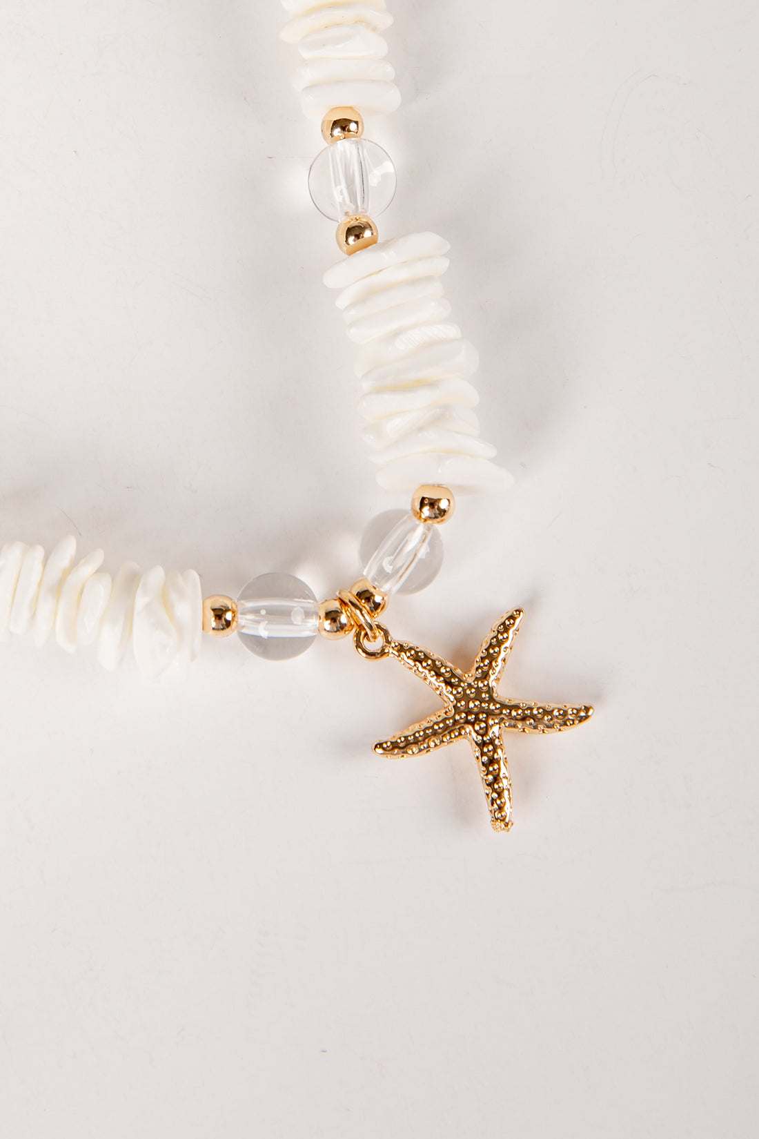 Bracelet with starfish charm and white beads on a light background