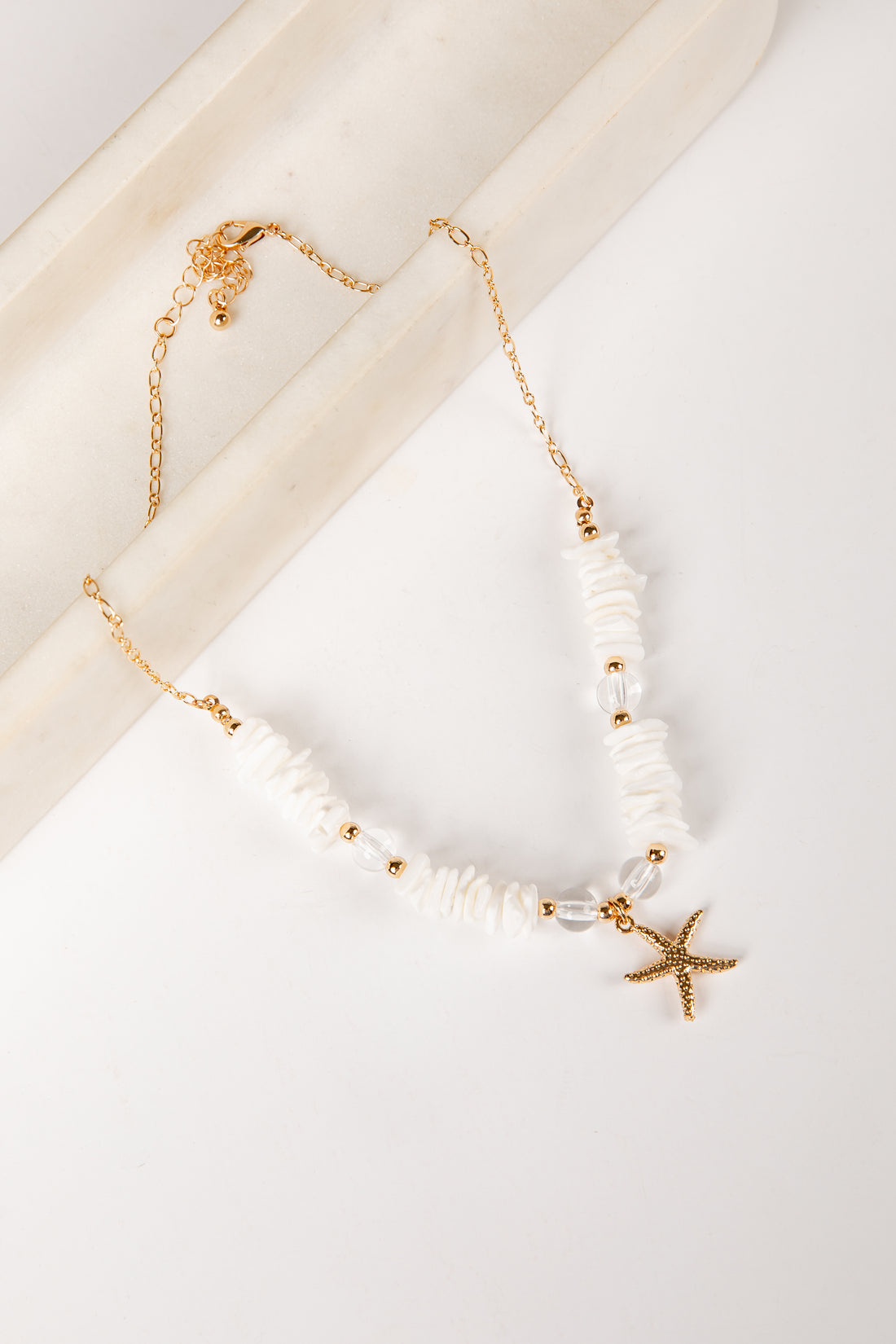 Pearl necklace with starfish charms on a white surface