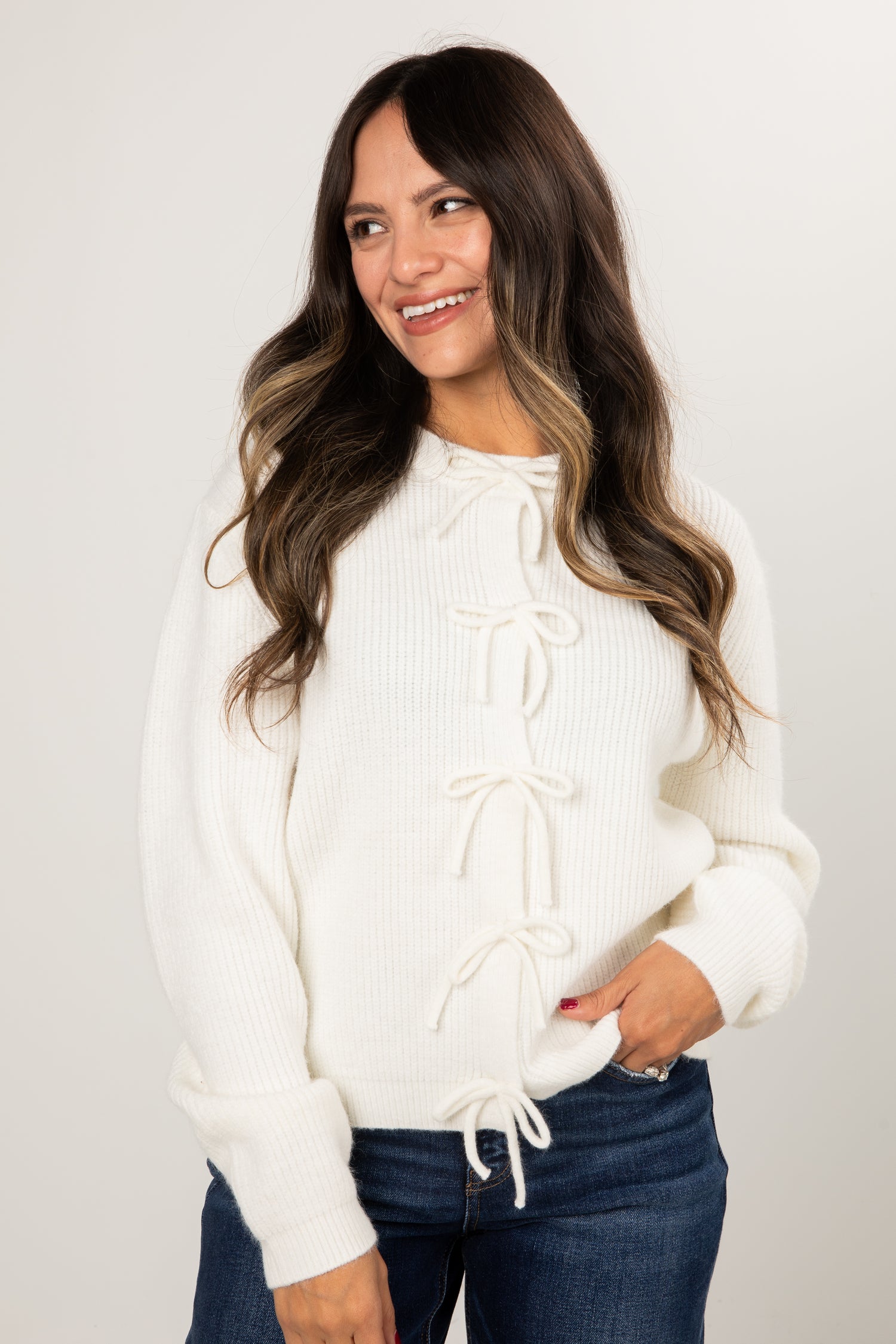 Woman wearing a white sweater with lace-up front design on a plain background