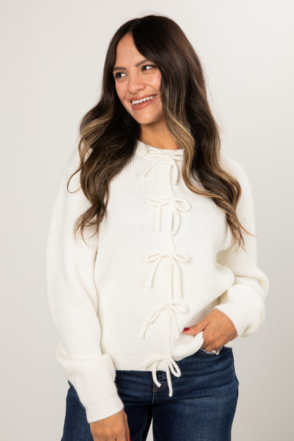 Woman wearing a white sweater with lace-up front design on a plain background