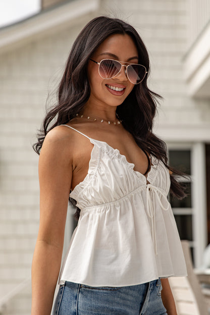 Woman wearing a white top and sunglasses with a blurred background