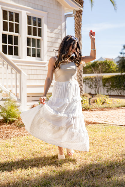 Woman in a white dress standing outdoors near a house