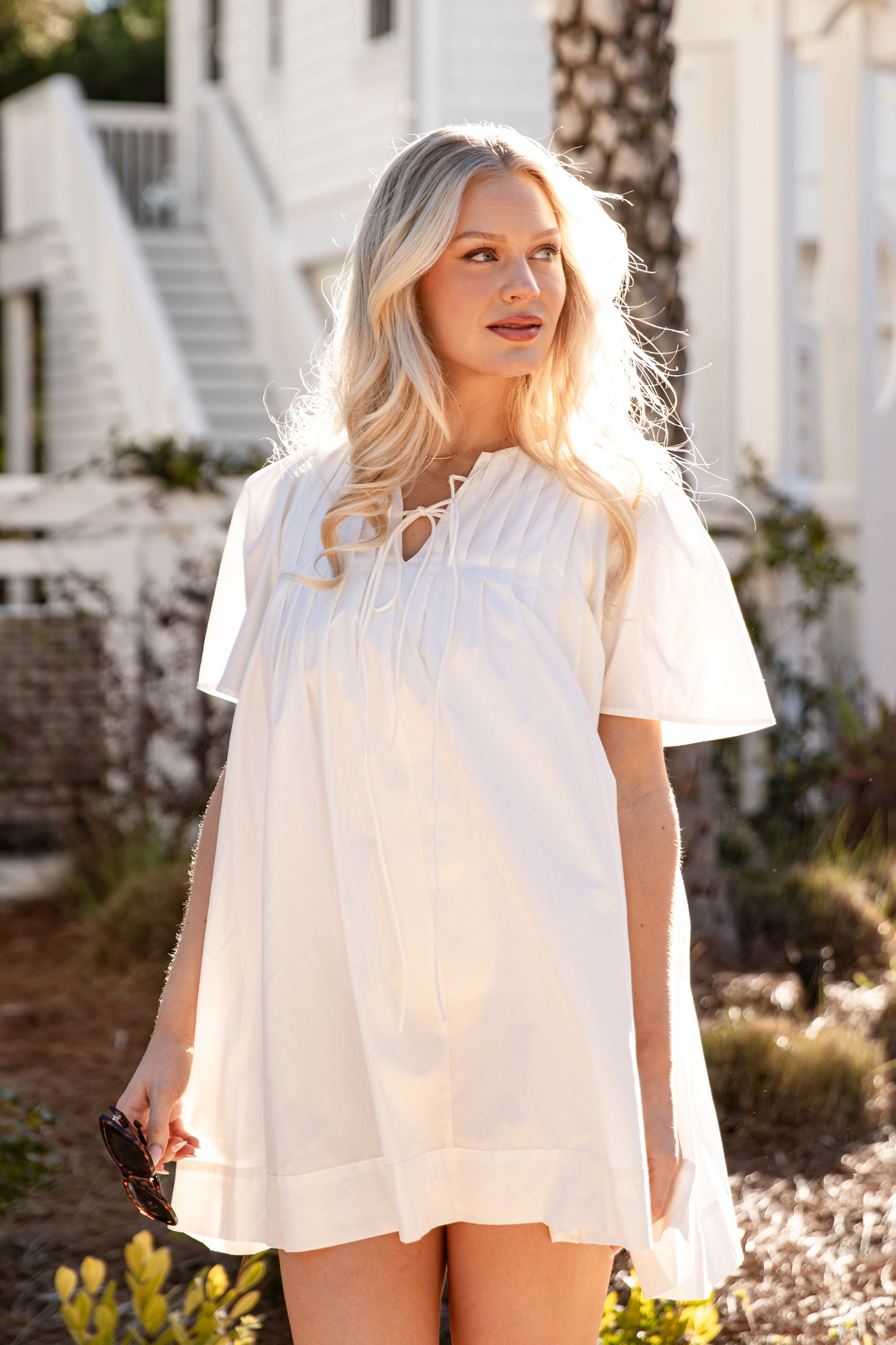 Woman in a white dress standing outdoors with a white building in the background