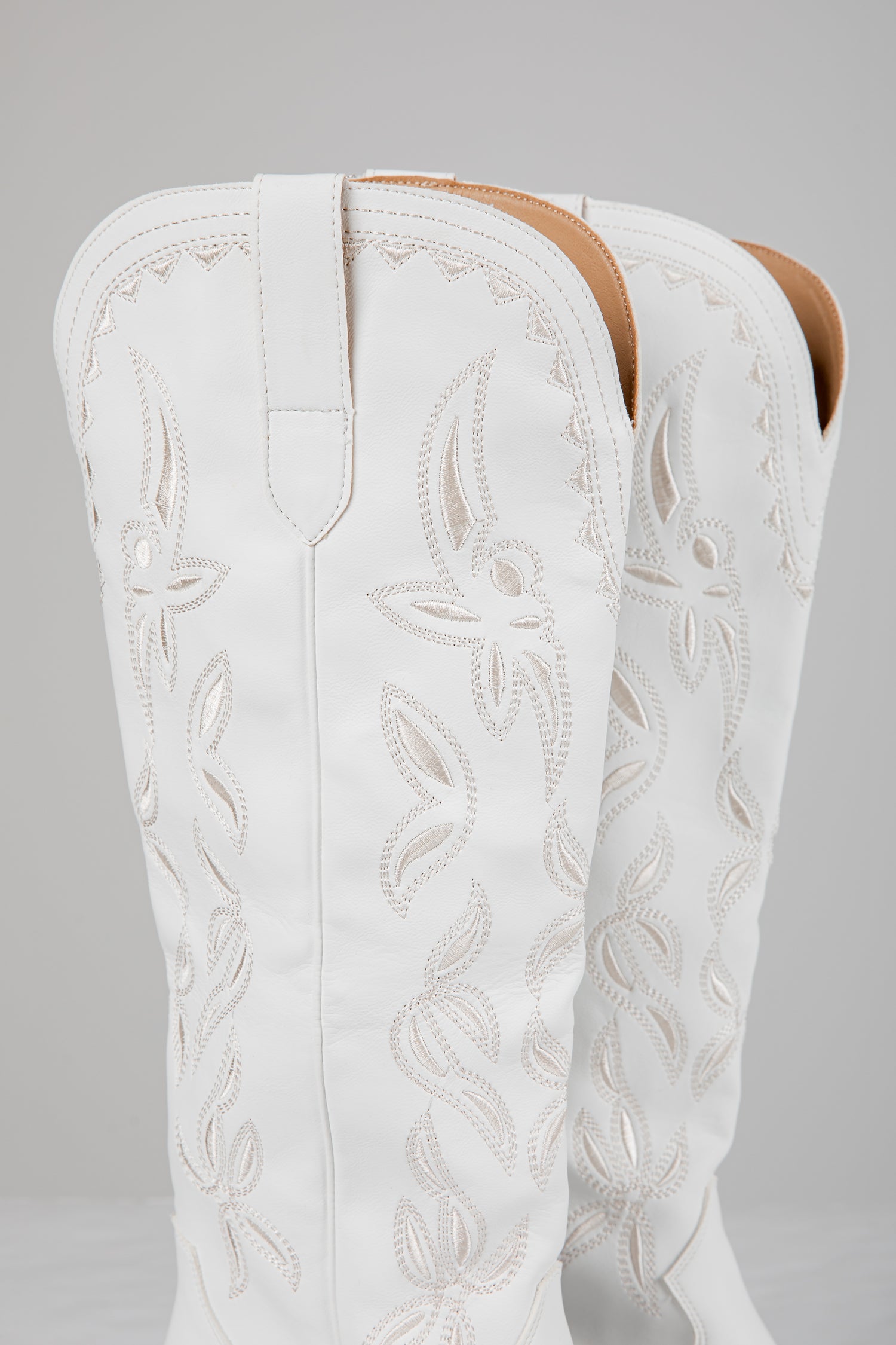 White embroidered cowboy boot on a gray background