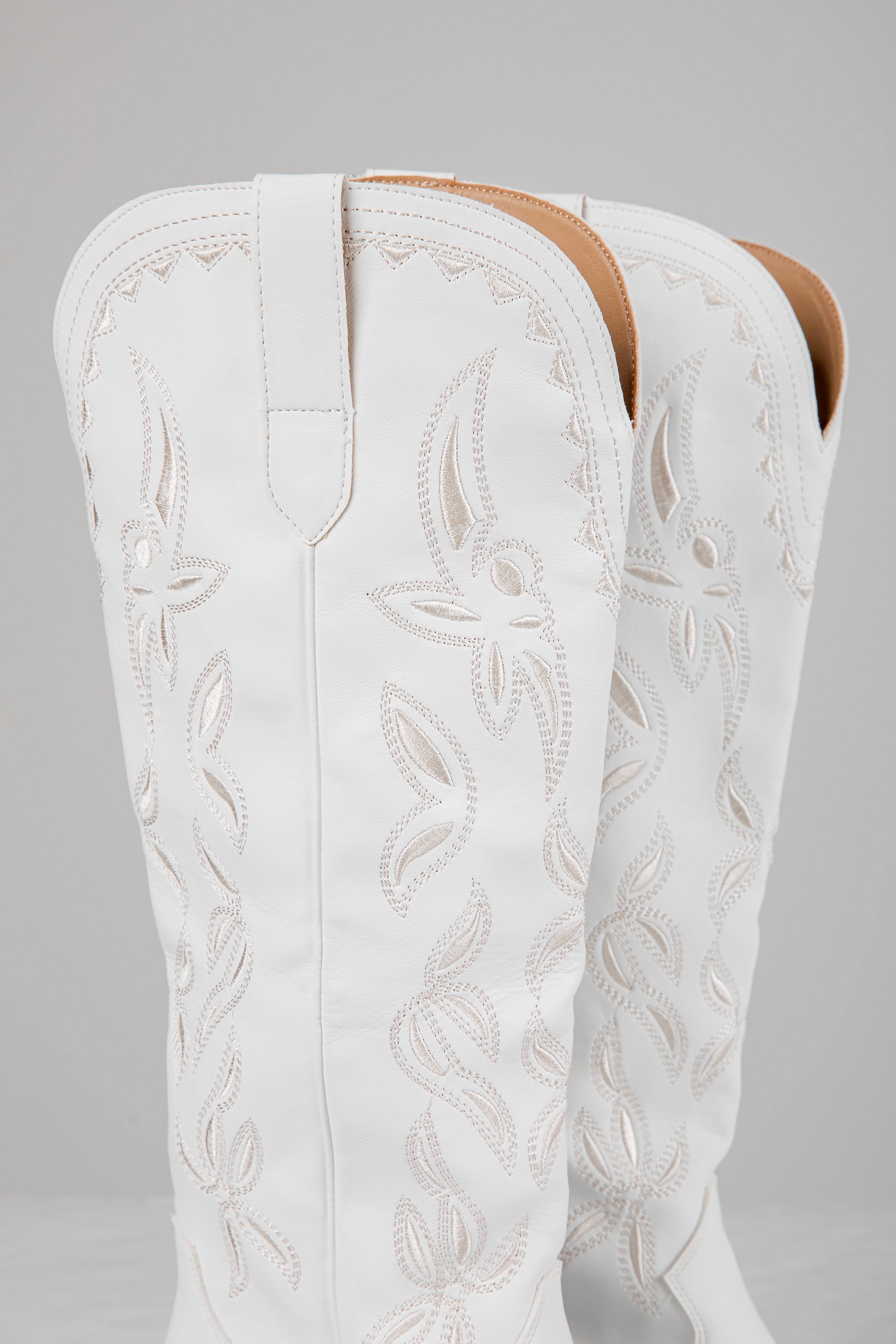 White embroidered cowboy boot on a gray background