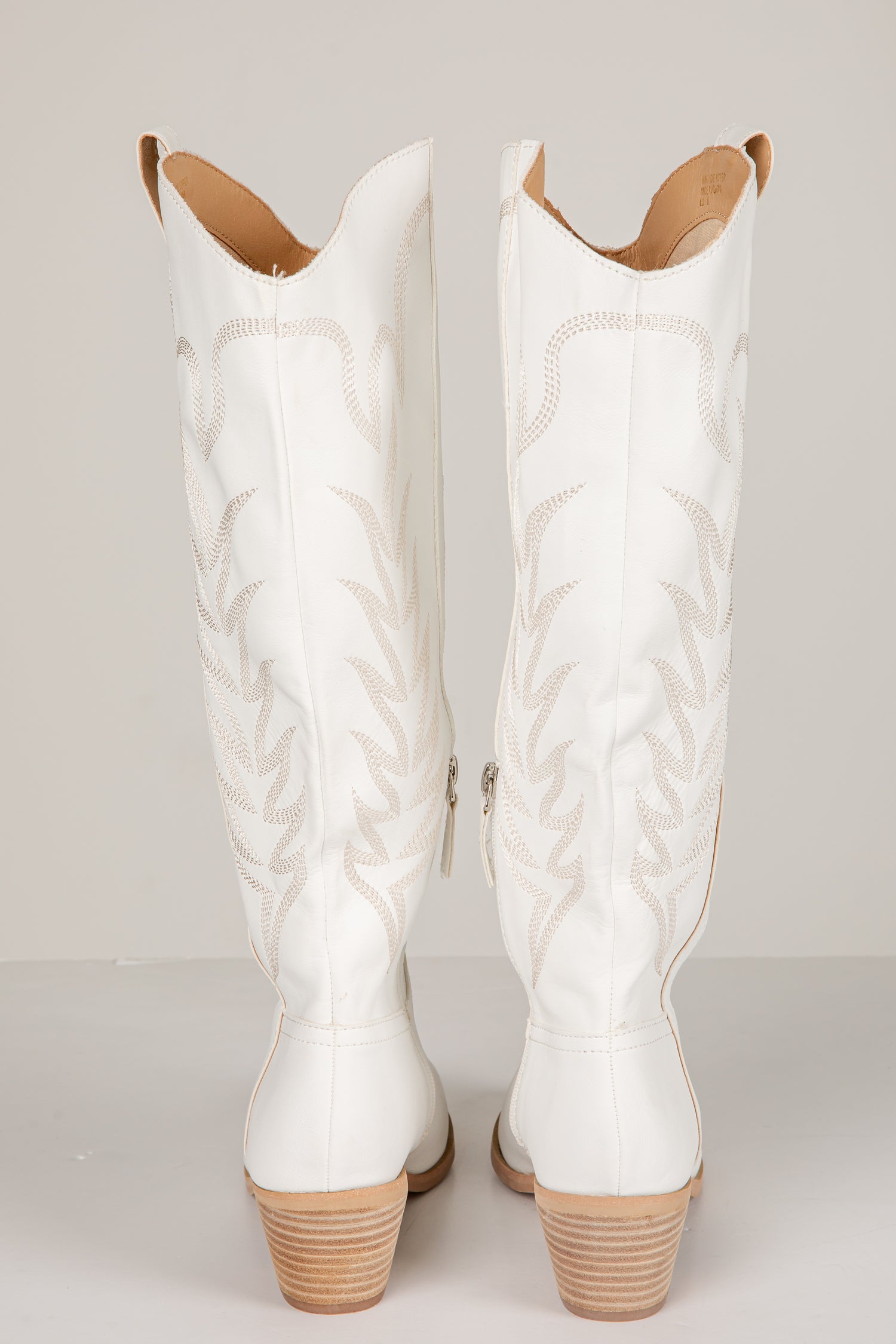 Pair of white quilted cowboy boots on a light gray background