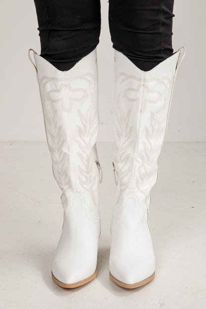 White embroidered knee-high boots on a white background