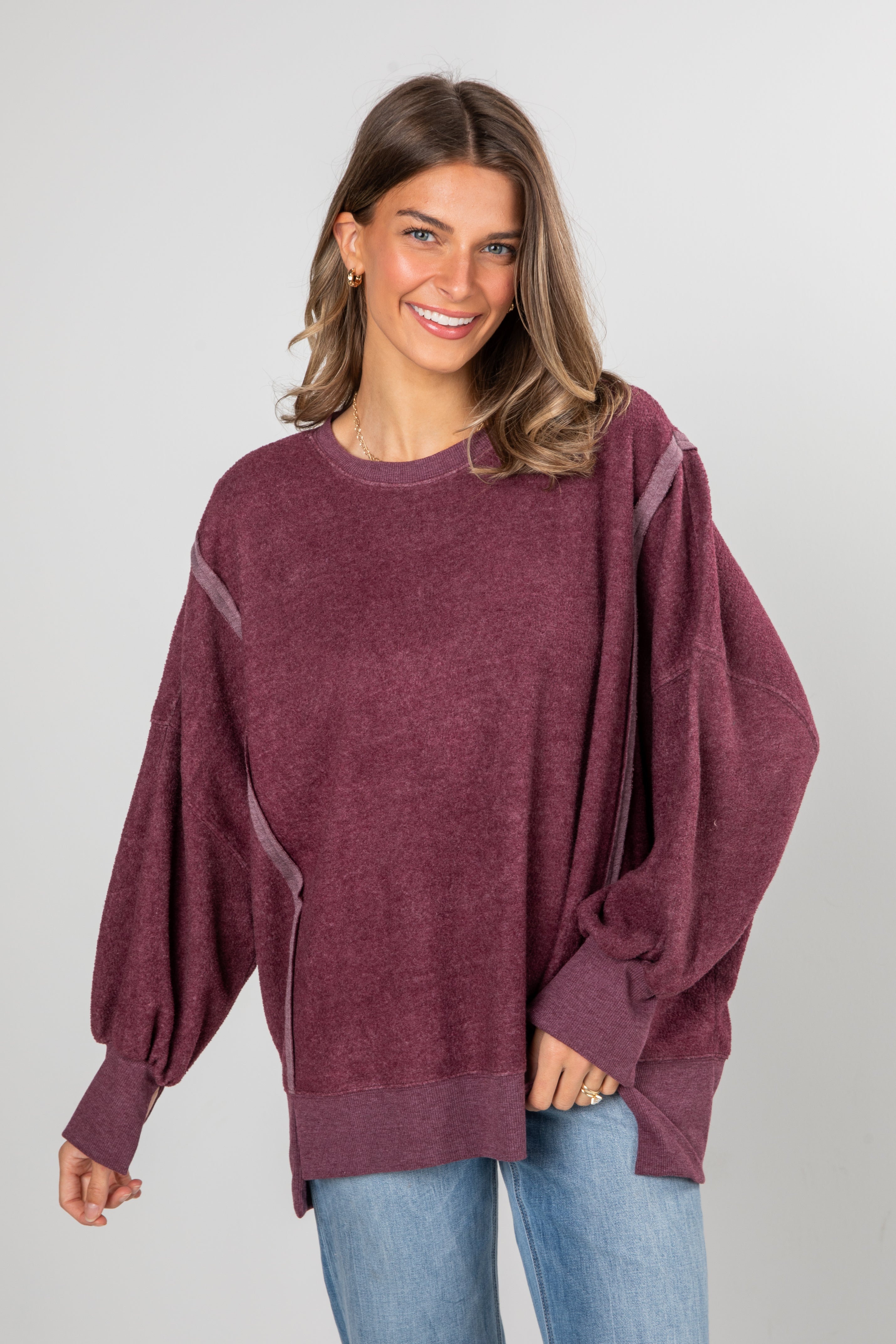 Woman wearing a burgundy sweater with a plain background