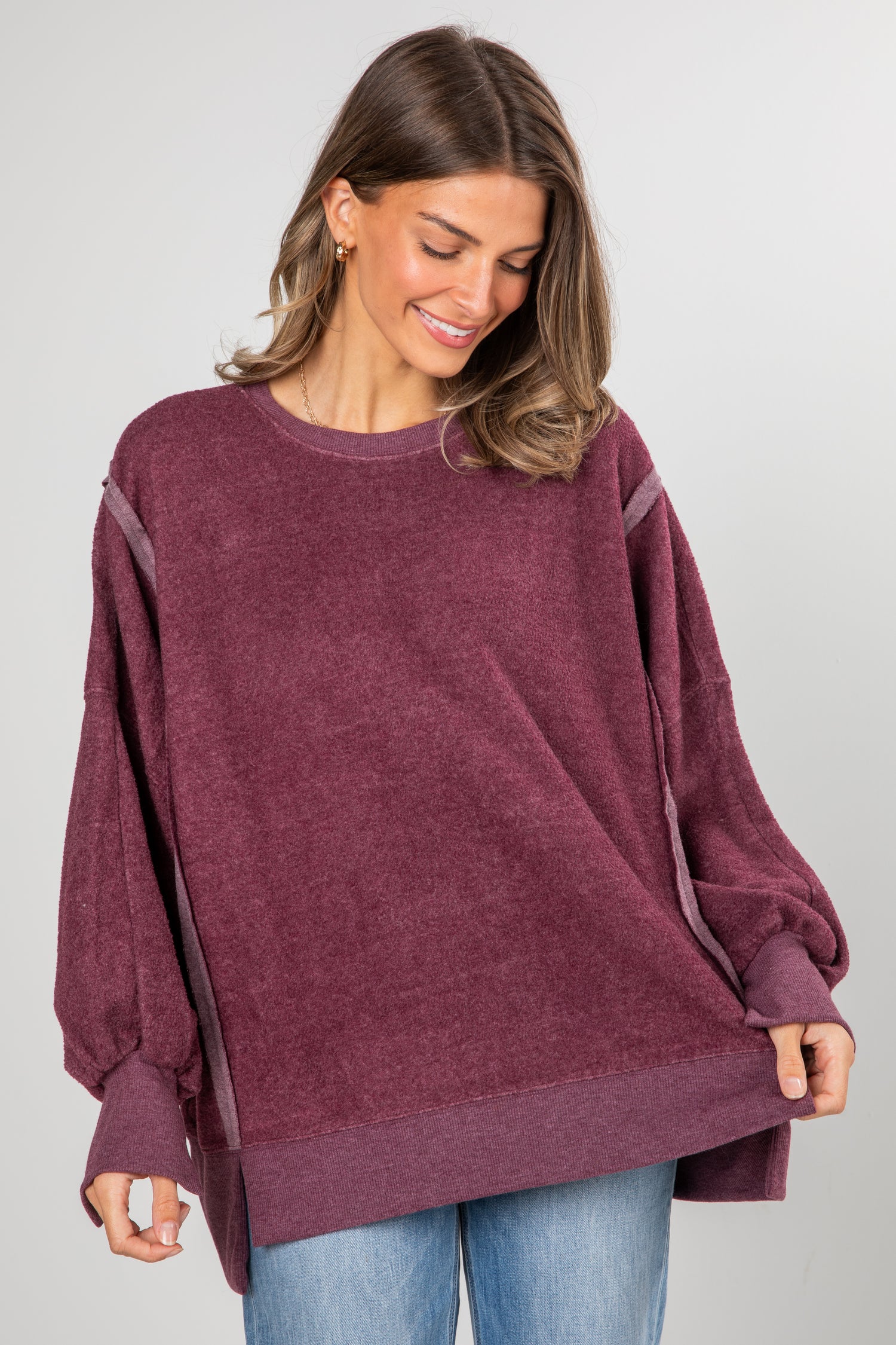 Woman wearing a maroon oversized sweater on a gray background