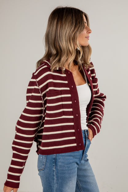 Woman wearing a maroon and white striped cardigan on a plain background